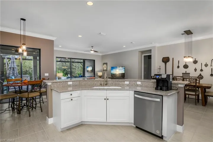 Kitchen with hanging light fixtures, sink, stainless steel dishwasher, ceiling fan, and white cabinetry