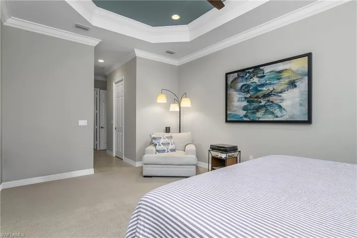 Carpeted bedroom with ceiling fan and ornamental molding