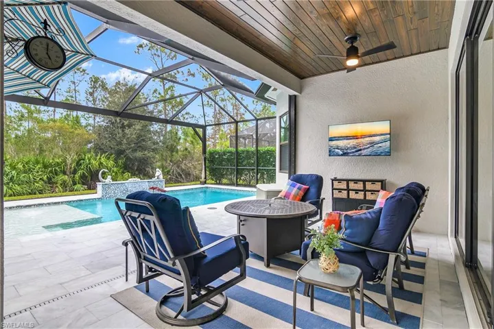 View of patio featuring a lanai, ceiling fan, and pool water feature