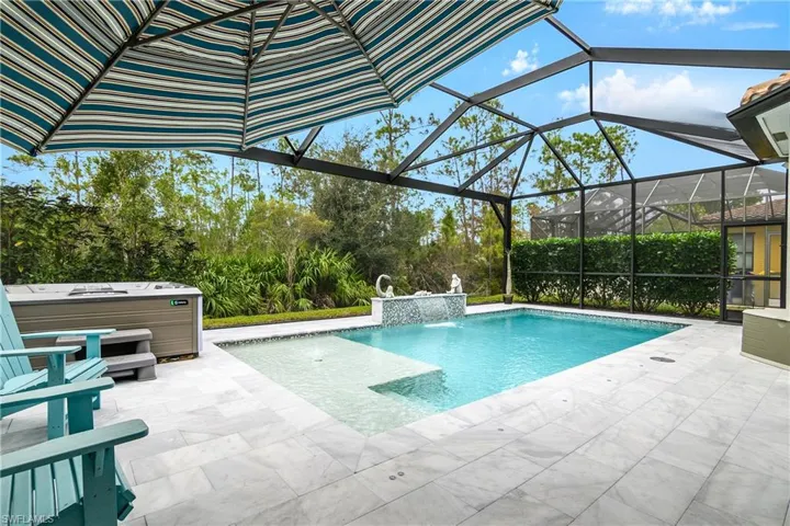 View of swimming pool with glass enclosure, a hot tub, pool water feature, and a patio area