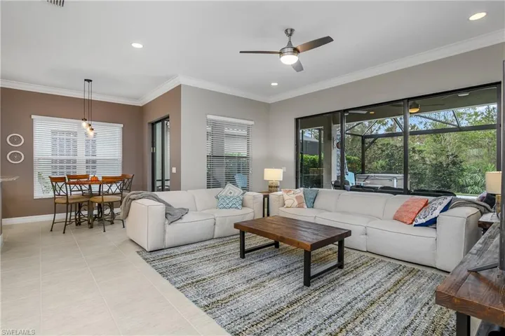 Living room with ornamental molding, ceiling fan, and light tile patterned flooring