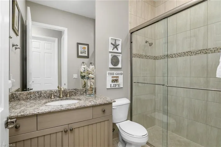 Bathroom with vanity, toilet, and a shower with door