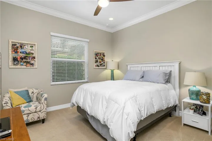 Carpeted bedroom with ceiling fan and ornamental molding