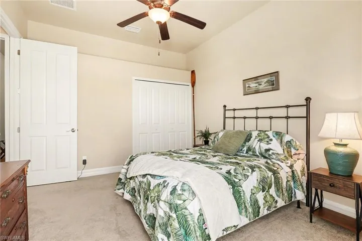 Bathed in tropical feature this guest bedrooms boasts a large closet, a ceiling fan, and light carpet.