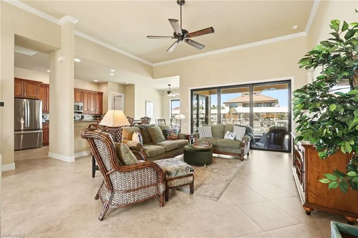 Living room with ceiling fan, crown molding, and luxury tile patterned flooring.