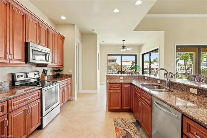 Kitchen featuring stainless steel appliances, quartz countertop, wood finish soft touch cabinetry, recessed lighting, and a ceiling fan located over the dining area.