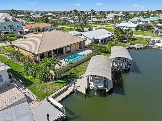 Aerial perspective of suburban area featuring the dual covered boat lifts and tropical yard and pool area.