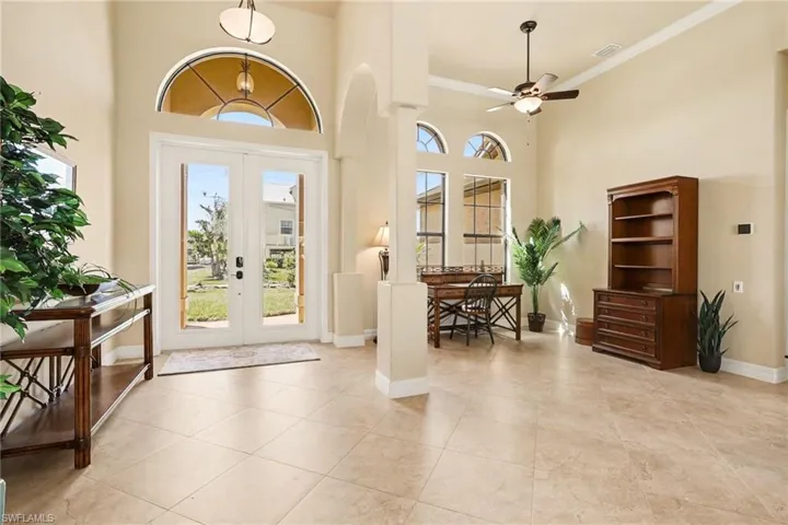 Entry way featuring a high ceiling, french doors, ceiling fan, and crown molding.