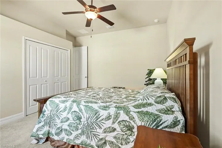 Bedroom with ceiling fan, light colored carpet, and a closet
