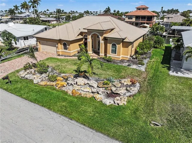 View of front facade featuring stucco exterior, a 2 car garage plus ample storage area and room for your golfcart, paved driveway, and landscaped front lawn area.