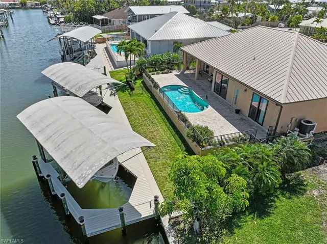 Aerial view the large dock area boasting two covered lifts, large pool deck and beautiful green space.