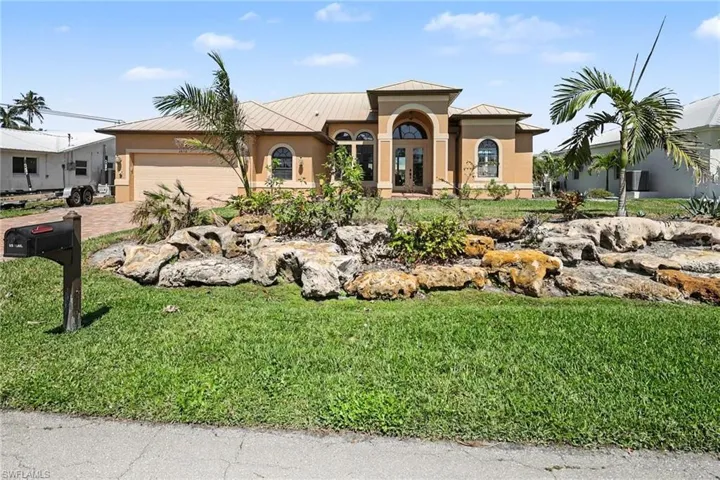 Beautifully landscaped home with a standing seam roof, stucco siding, and attached 2 car garage.