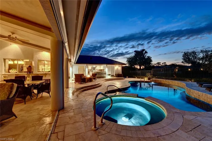 Pool at dusk featuring an in ground lighted hot tub and pool