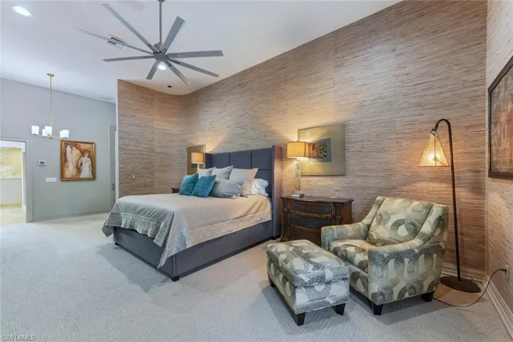 Carpeted bedroom with newer ceiling fan and sitting space.