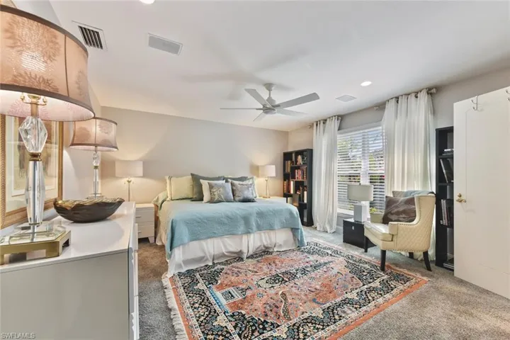 Guest bedroom featuring a walk-in closet, full bath, lighted ceiling fan.