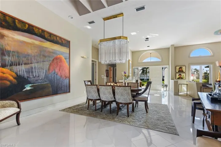 Spacious dining area with white marble floors and stunning chandelier.