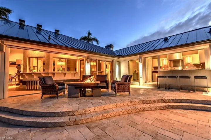 Patio terrace at dusk with an outdoor bar and an outdoor fire pit