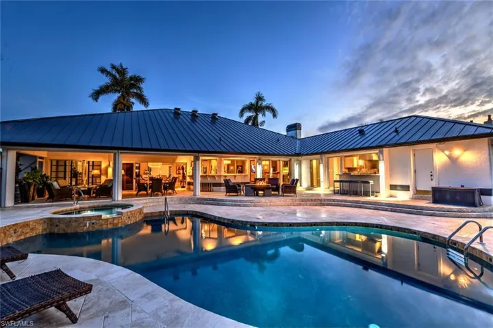 Pool at dusk with an outdoor living space, a patio area, and an in ground pool & hot tub
