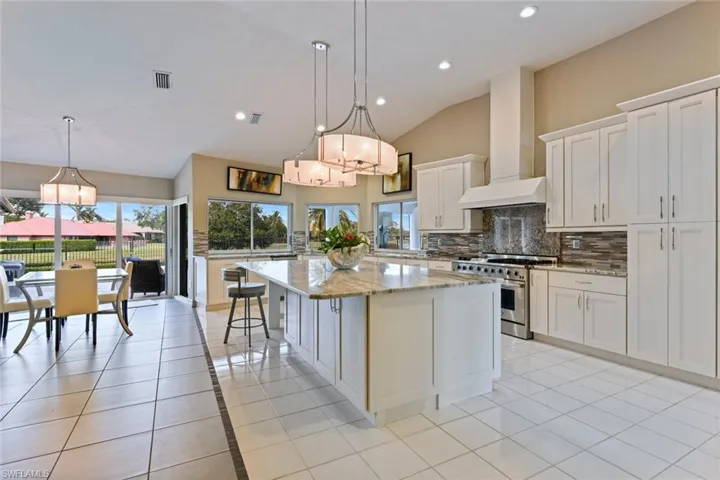 Kitchen with white cabinets, custom range hood, stainless steel stove, and a kitchen island