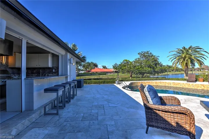View of patio / terrace with a water view, bar seating off the outdoor kitchen, and a fenced in pool