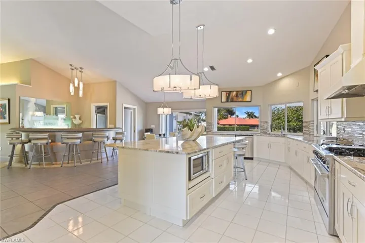 Kitchen with tasteful backsplash, a breakfast bar, stainless steel appliances, a kitchen island, and light tile flooring