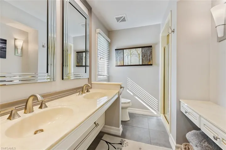 Bathroom with tile floor, double-vanity, and walk-in shower.