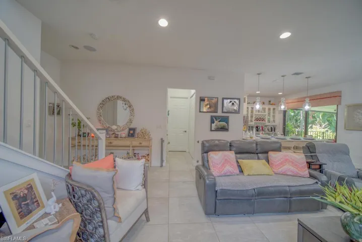 Living area with stairway, light tile patterned flooring, and recessed lighting