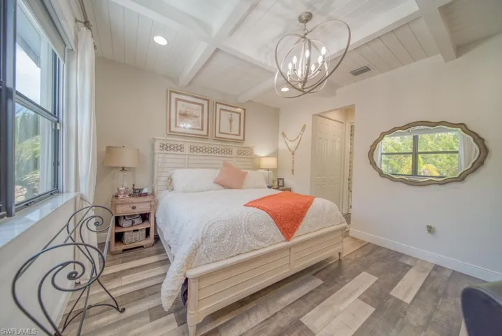Bedroom with an inviting chandelier, wood-type flooring, a closet, and beam ceiling
