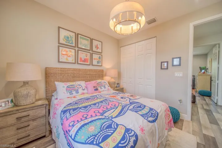 Bedroom with light wood-type flooring, a closet, and an inviting chandelier