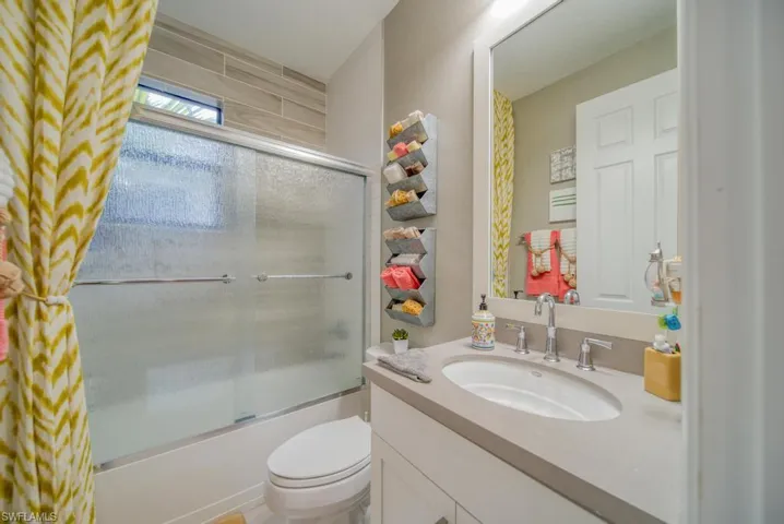 Full bathroom featuring toilet, vanity, and shower / bath combination with glass door