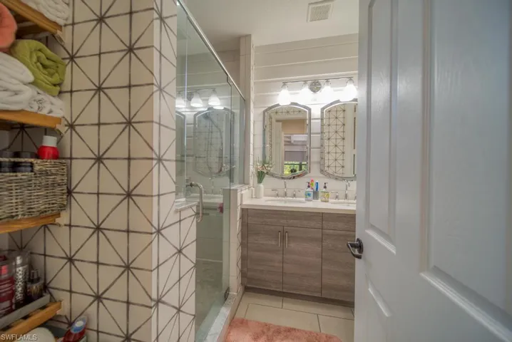Bathroom featuring a shower with shower door, vanity, and tile patterned floors