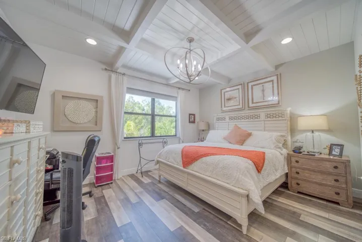 Bedroom featuring beamed ceiling, a chandelier, wood-type flooring, and coffered ceiling