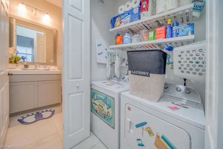 Laundry room with sink, light tile patterned flooring, and washer and clothes dryer