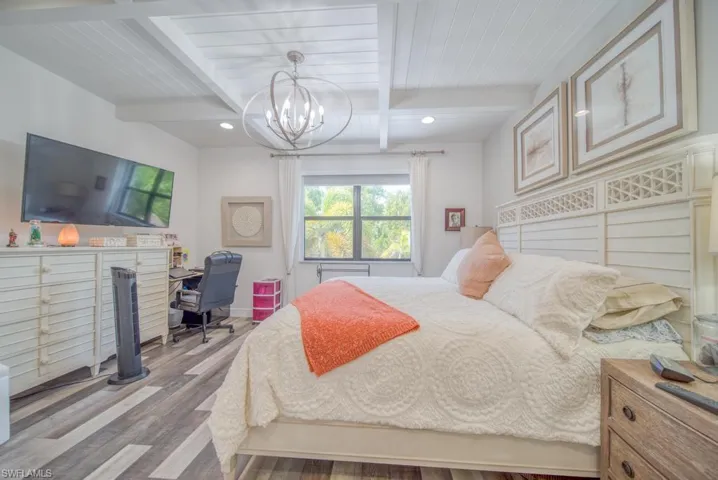 Bedroom featuring beam ceiling, a notable chandelier, and light hardwood / wood-style flooring