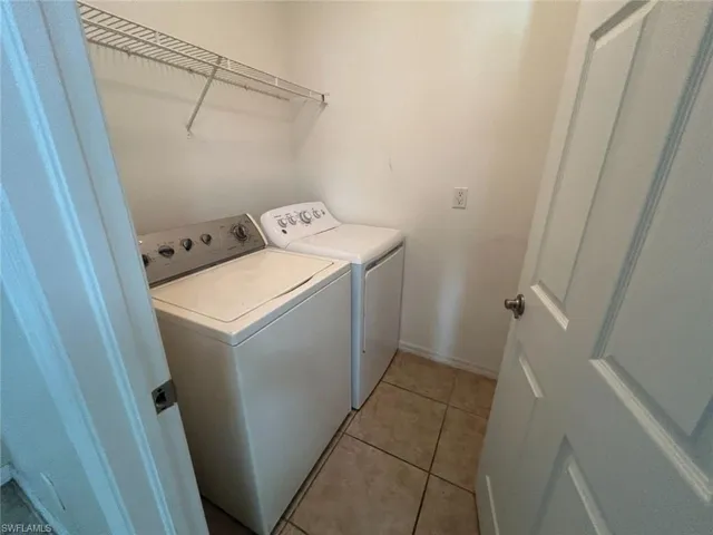 Clothes washing area featuring light tile patterned floors and independent washer and dryer