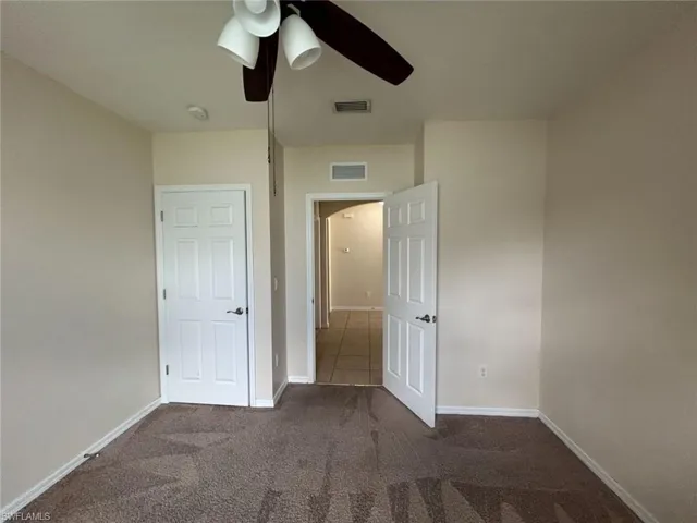 Unfurnished bedroom featuring carpet floors, visible vents, baseboards, and a ceiling fan
