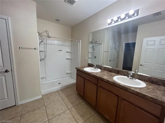 Bathroom with walk in shower, tile patterned flooring, a sink, and visible vents