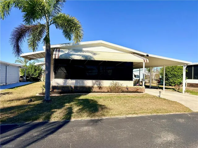 Manufactured / mobile home featuring a front yard, an attached carport, and driveway
