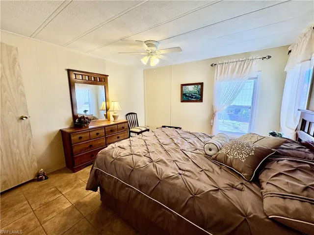 Tiled bedroom with ceiling fan and a textured ceiling