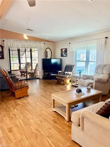 Living room featuring light wood-style flooring, ceiling fan, and lofted ceiling