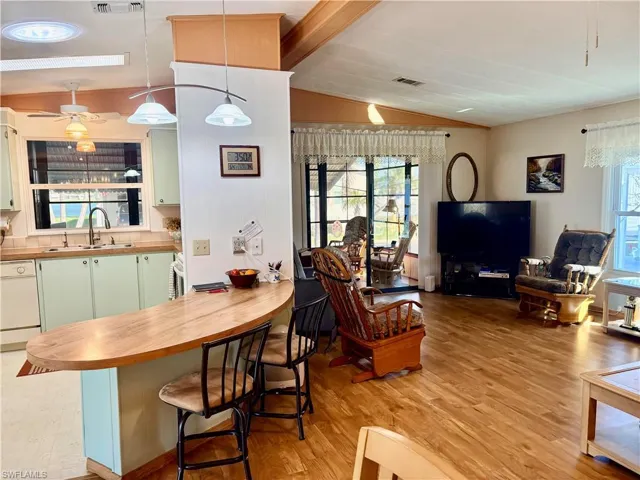 Living room featuring light wood-type flooring, ceiling fan, healthy amount of natural light, and vaulted ceiling with beams