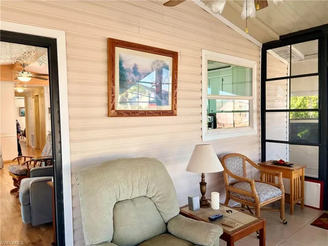 Living area featuring ceiling fan, wood walls, and vaulted ceiling