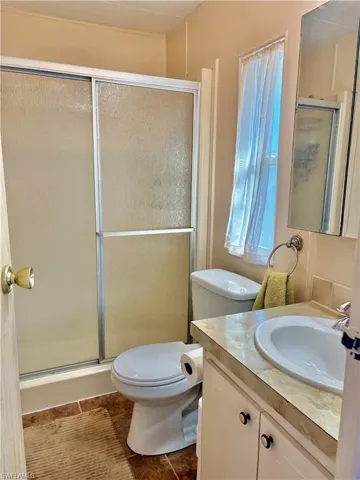 Bathroom featuring vanity, a shower stall, and dark tile patterned floors