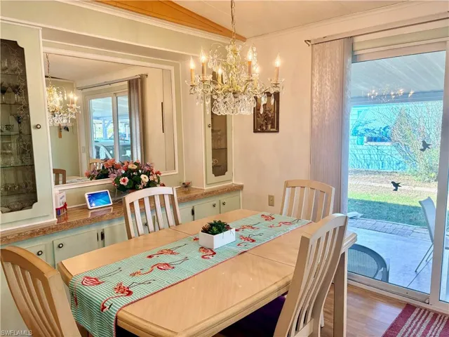 Dining space featuring suspended lighting, ornamental molding, wood finished floors, and lofted ceiling