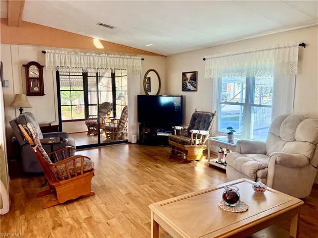Living area featuring vaulted ceiling with beams, light wood-style flooring, and crown molding