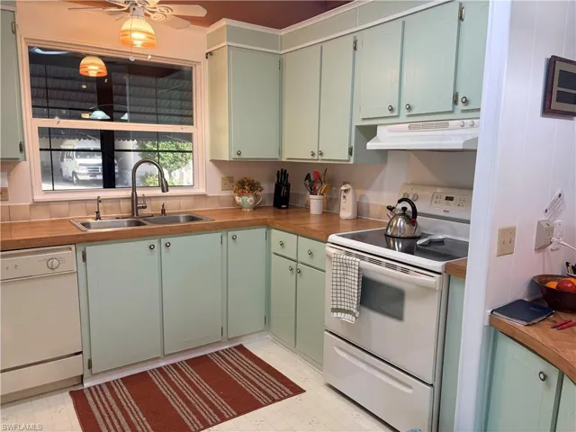 Kitchen featuring green cabinetry, white appliances, light flooring, ceiling fan, and butcher block countertops