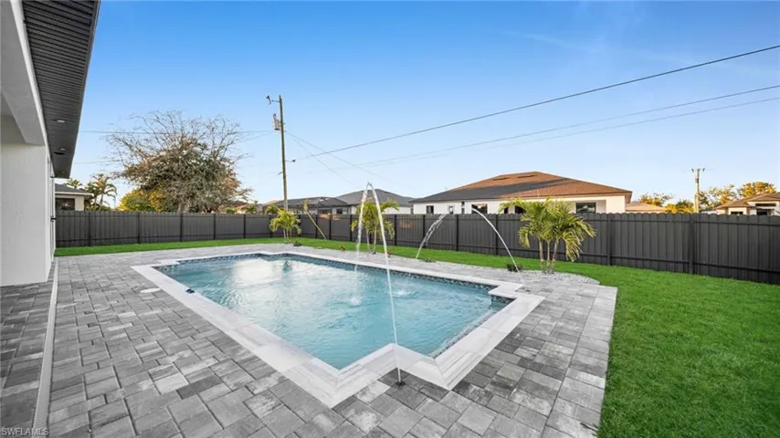View of swimming pool with exterior kitchen, patio surround, and a fenced backyard