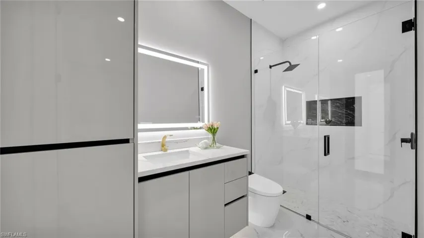 Bathroom with vanity, a marble finish shower, recessed lighting, and marble tiled flooring