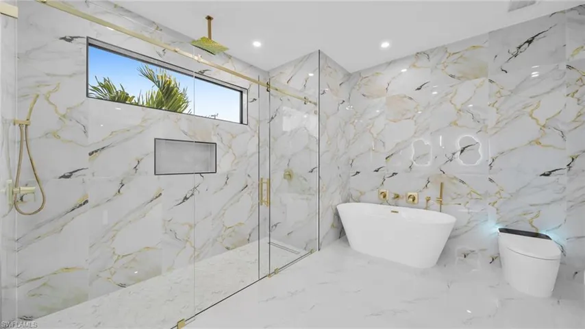 Full bath with stone wall, a marble finish shower, a freestanding tub, and recessed lighting
