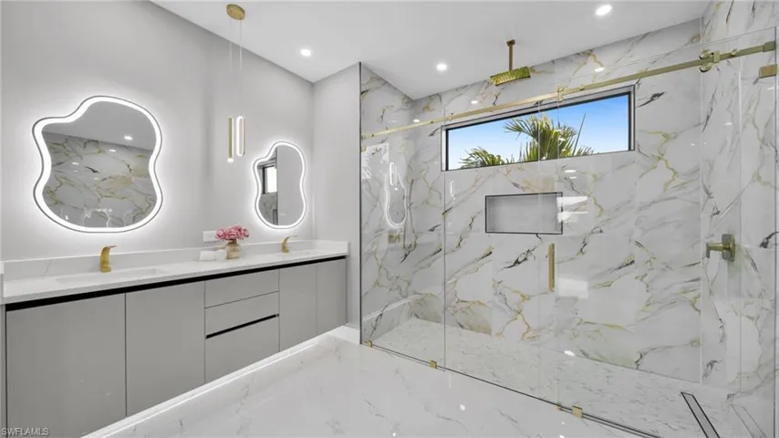 Bathroom with a marble finish shower, double vanity, recessed lighting, stone wall, and marble tiled floors